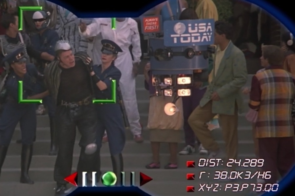 <p><strong>Figure 1.3</strong> Doc Brown takes a closer look through his futuristic binoculars, and we can see the drone and logo in more detail. It also bears a read sign that reads “Always There First!” in all uppercase, white lettering.</p>